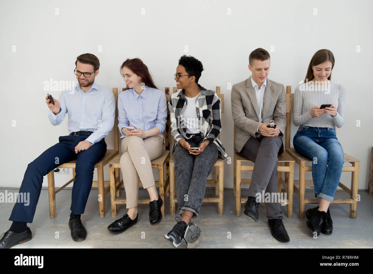 Diversi giovani smartphone utilizzando mentre erano in attesa in coda Foto Stock