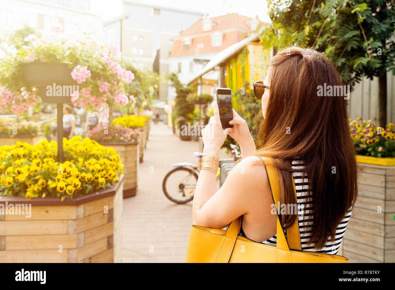 Donna su city tour di scattare una foto di bellissimi fiori cafe con il suo smartphone Foto Stock