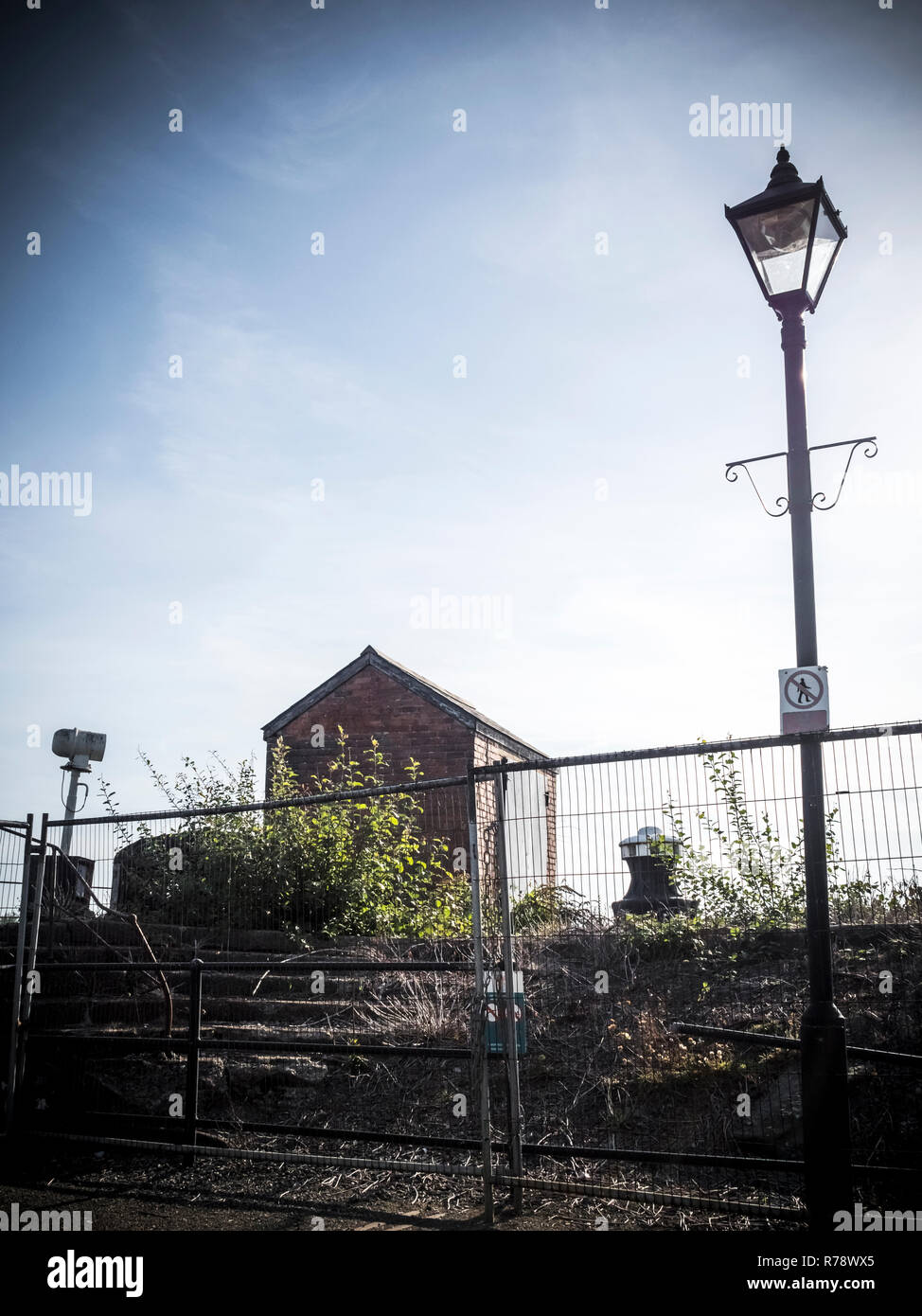 Di piccole dimensioni isolata abbandonato edificio di mattoni, shack o capannone, dietro una recinzione temporanea Foto Stock