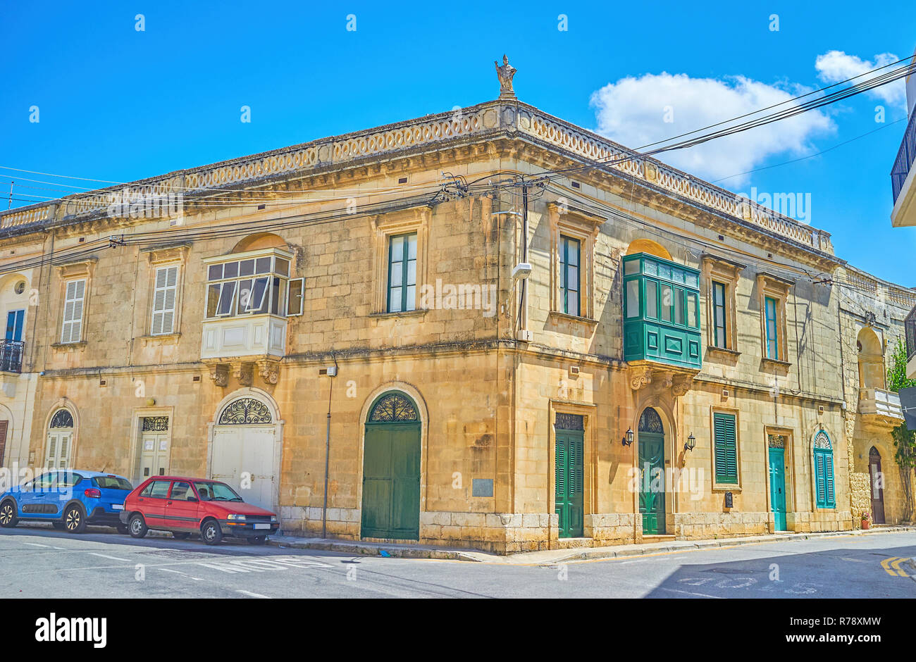 Il vecchio edificio Maltese con i tipici balconi e la scultura di un santo su un angolo del tetto, città mista, Malta Foto Stock
