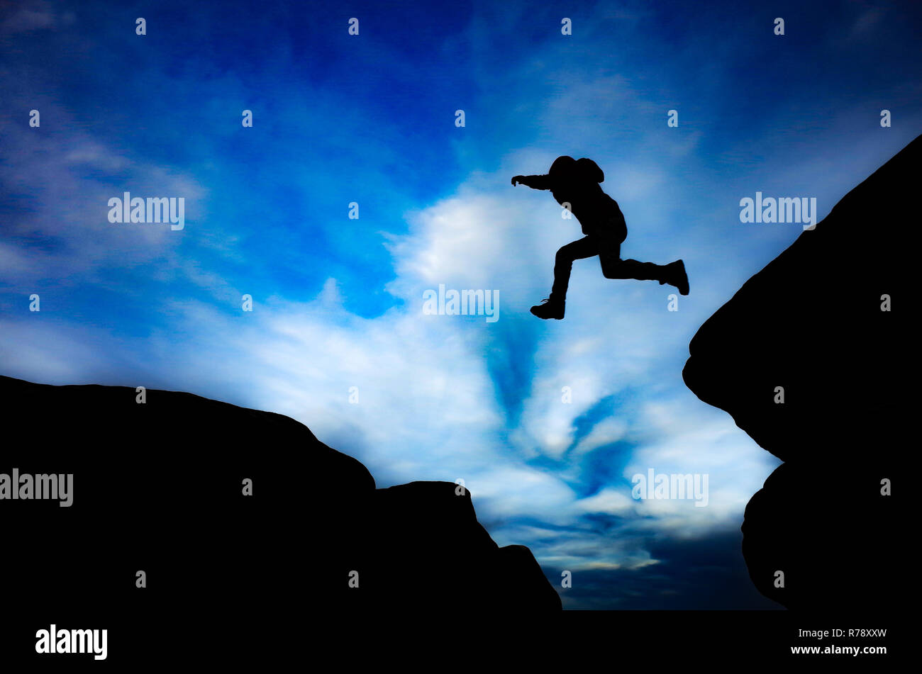 Silhouette di boy il salto tra le rocce Foto Stock