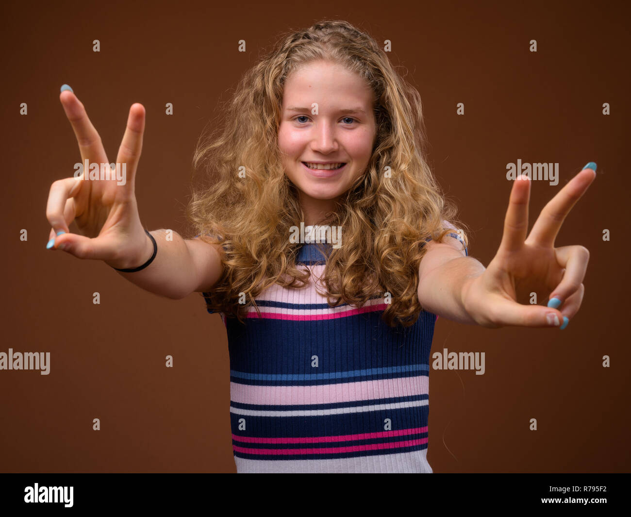 Giovane bella bionda ragazza sorridente e facendo segno di pace gesto Foto Stock