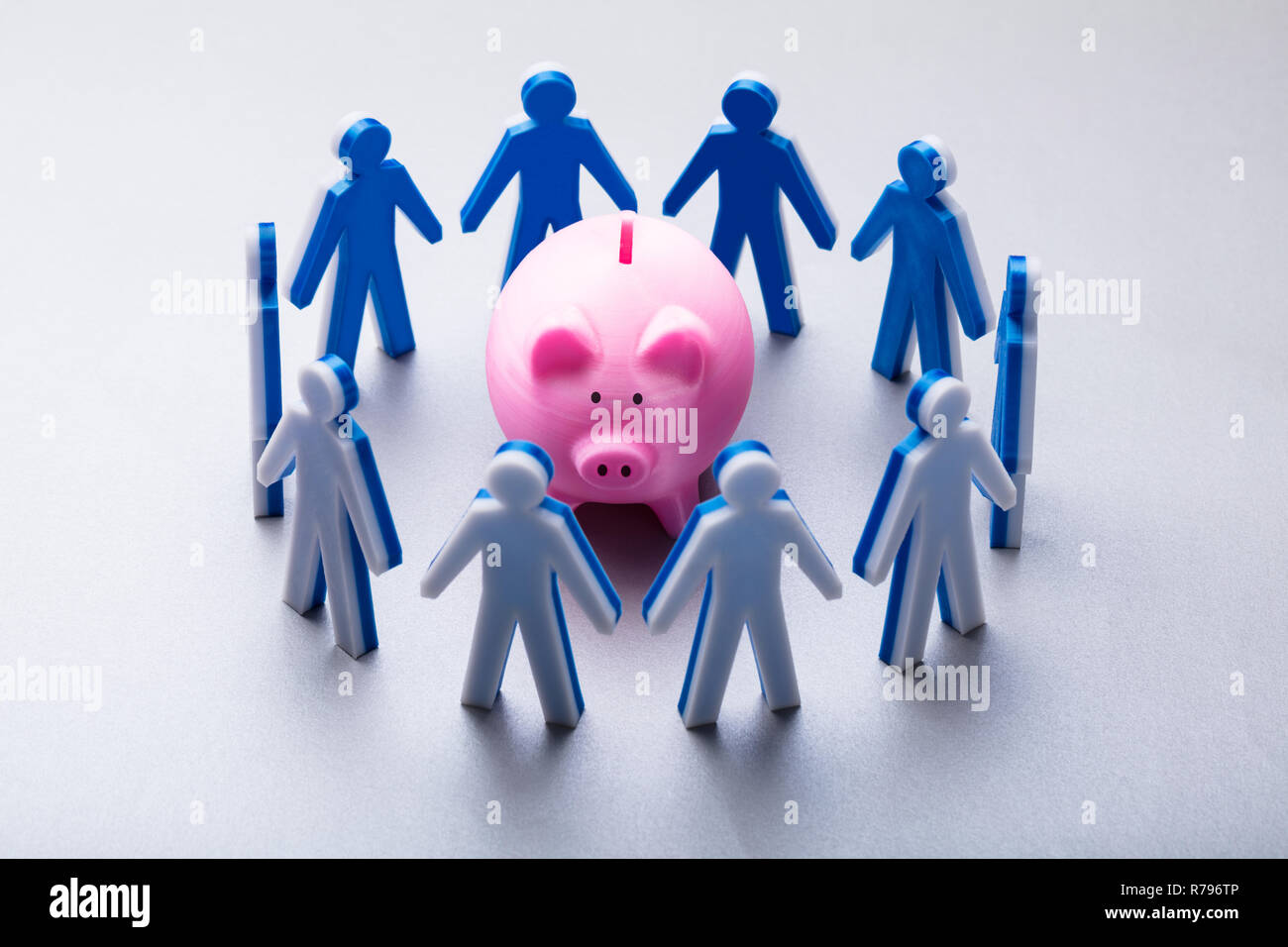 Le figure umane rosa circostante Piggybank Foto Stock