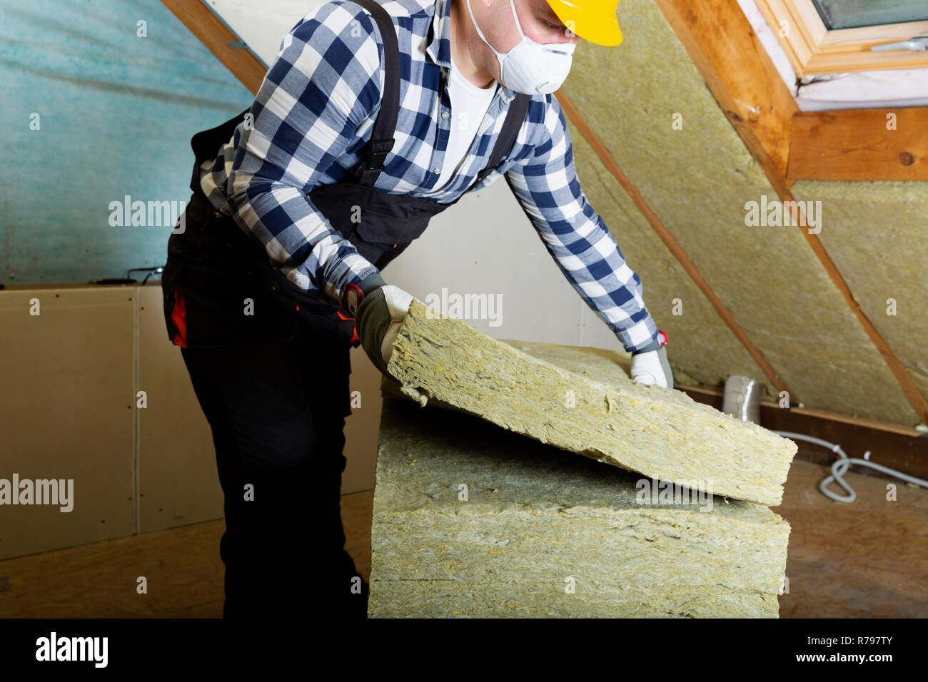 L'uomo installazione tetto termica dello strato di isolamento - utilizzando pannelli in fibra minerale. Soffitta il rinnovamento e il concetto di isolamento Foto Stock