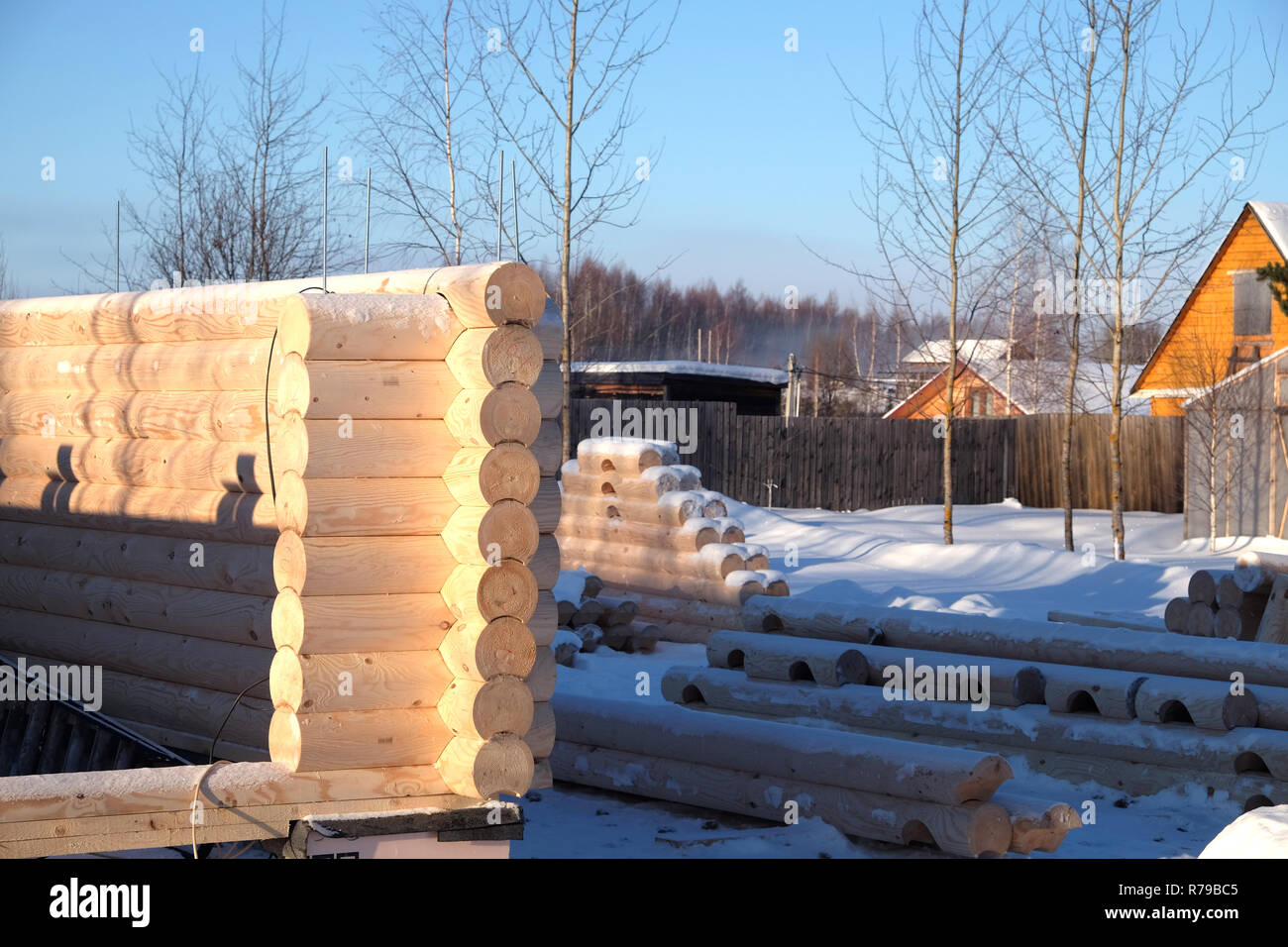 Costruzione di legname per la casa. Molti registri liscia preparato per la costruzione giacente in righe sulla neve nella soleggiata giornata invernale. La foto in orizzontale Foto Stock