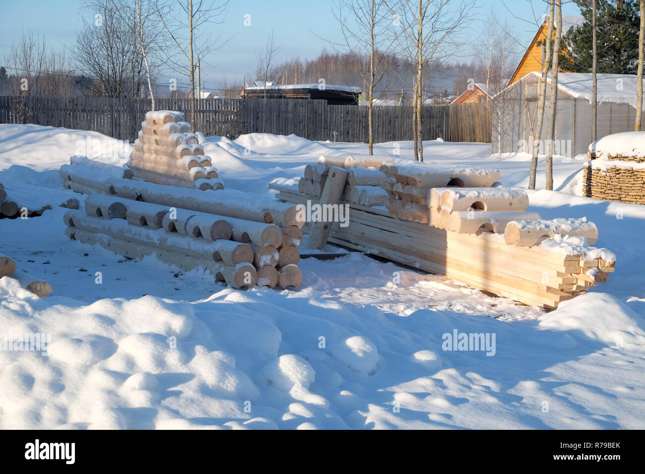 Costruzione di legname per la casa. Molti registri liscia preparato per la costruzione giacente in righe sulla neve nella soleggiata giornata invernale. La foto in orizzontale Foto Stock