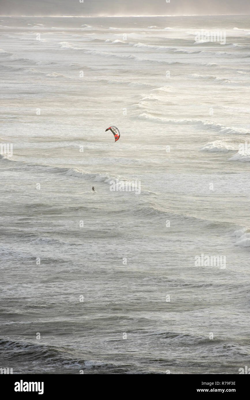 Un Kite surfer in mare mosso e onde della costa del Devon Regno Unito Foto Stock