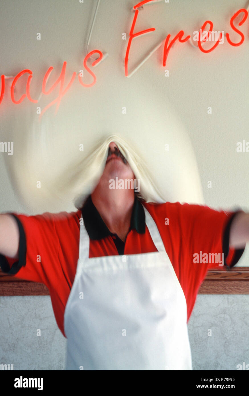 Lo Chef invano tossing impasto pizza al suo small business pizzeria, STATI UNITI D'AMERICA Foto Stock