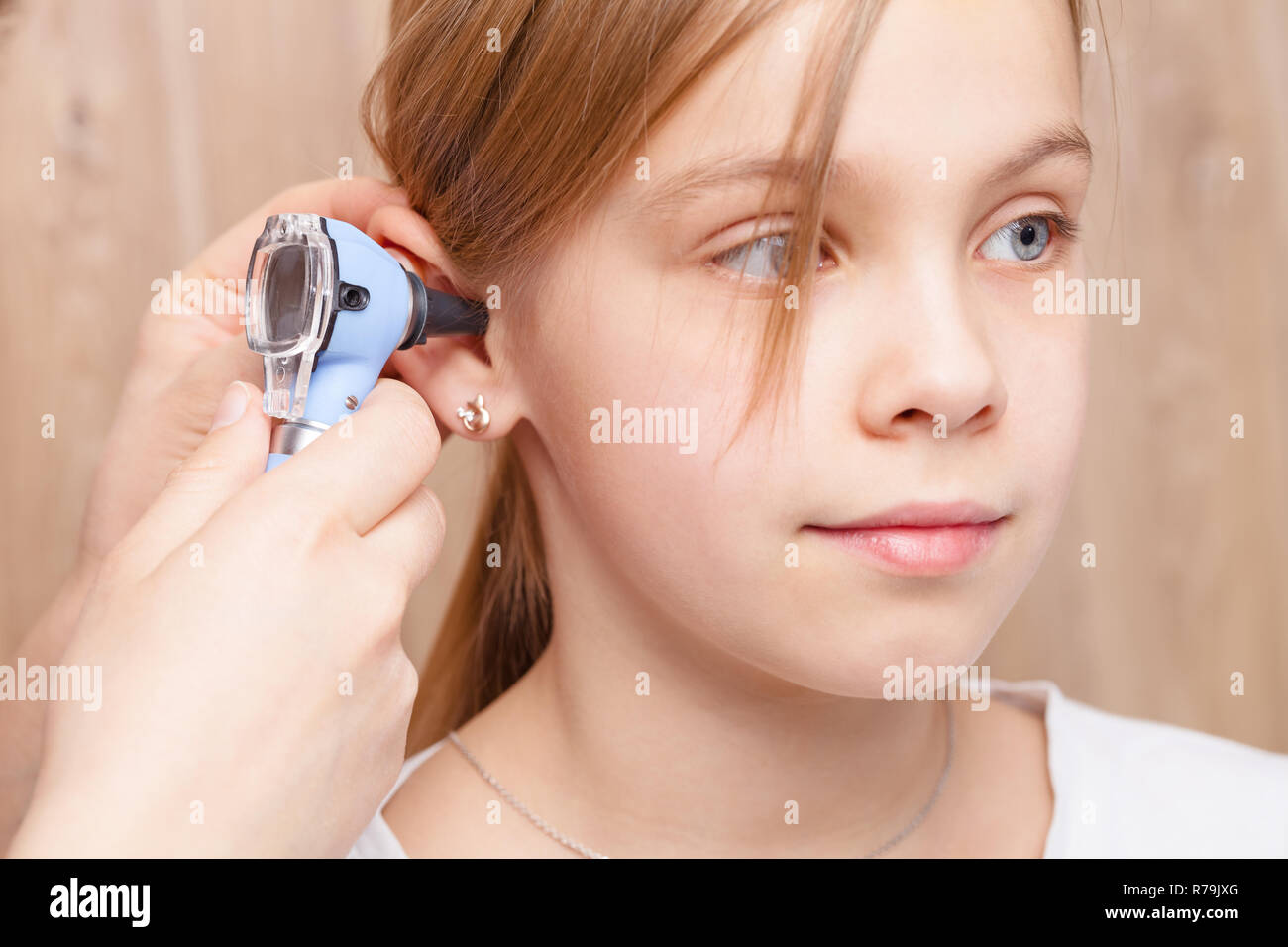 Femmina esamina pediatra elementari di età ragazza l orecchio. Medico utilizzando un otoscopio o auriscope per controllare il canale uditivo e la membrana del timpano. Bambino ENT controllare Foto Stock
