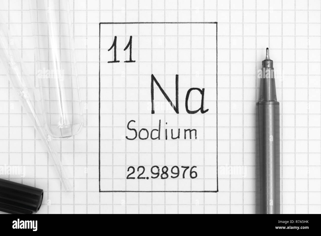 Tavola periodica degli elementi. La grafia elemento chimico sodio Na con la penna nera, tubo di prova e la pipetta. Close-up. Foto Stock