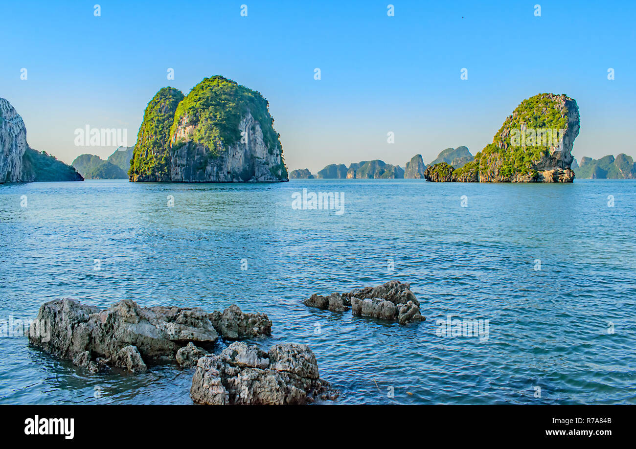 Un cluster di piccole rocce grigie nella parte anteriore di due pietre calcaree carsiche nella baia di Halong Vietnam Novembre 2018 Foto Stock