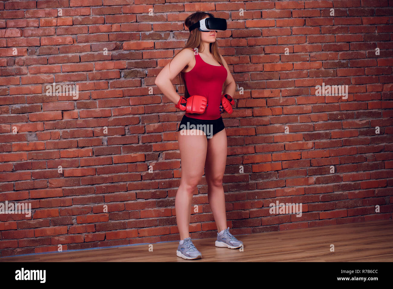 Giovani fighter boxer montare la ragazza di occhiali VR indossando guanti da boxe in formazione Foto Stock