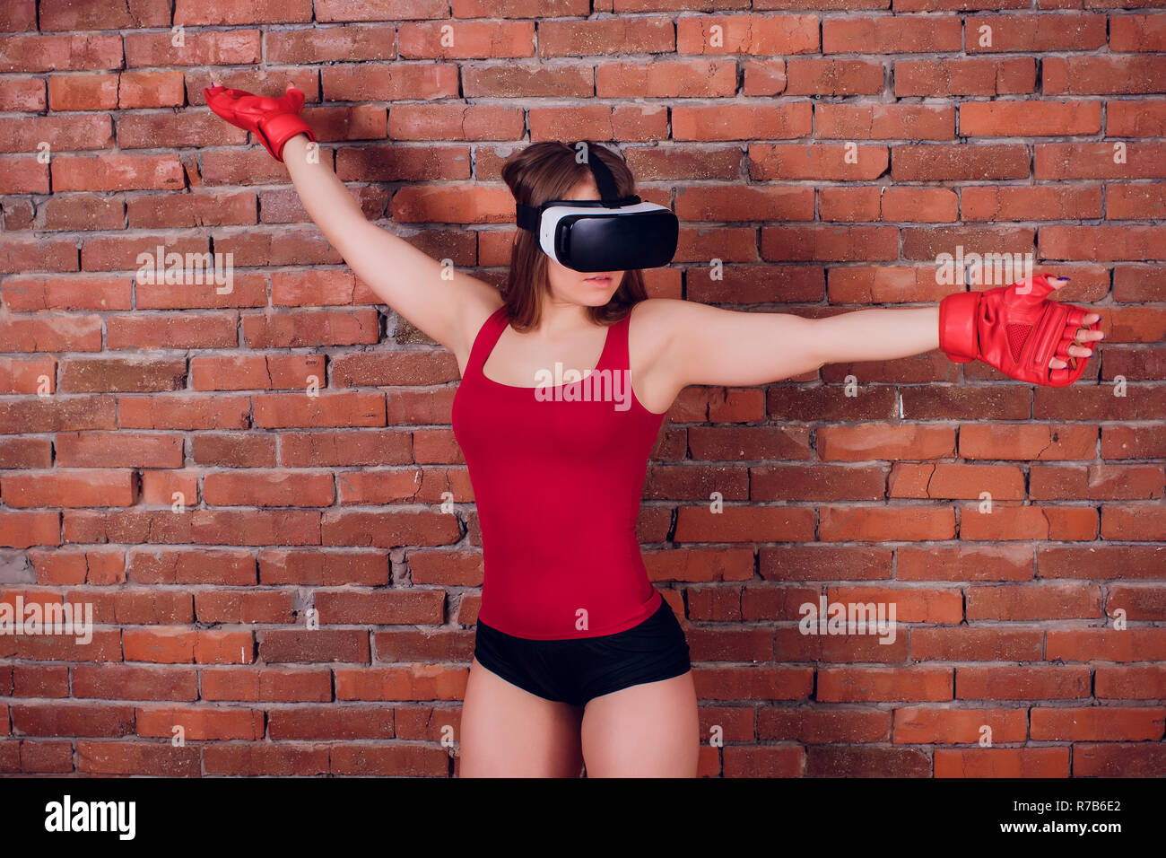 Giovani fighter boxer montare la ragazza di occhiali VR indossando guanti da boxe in formazione Foto Stock
