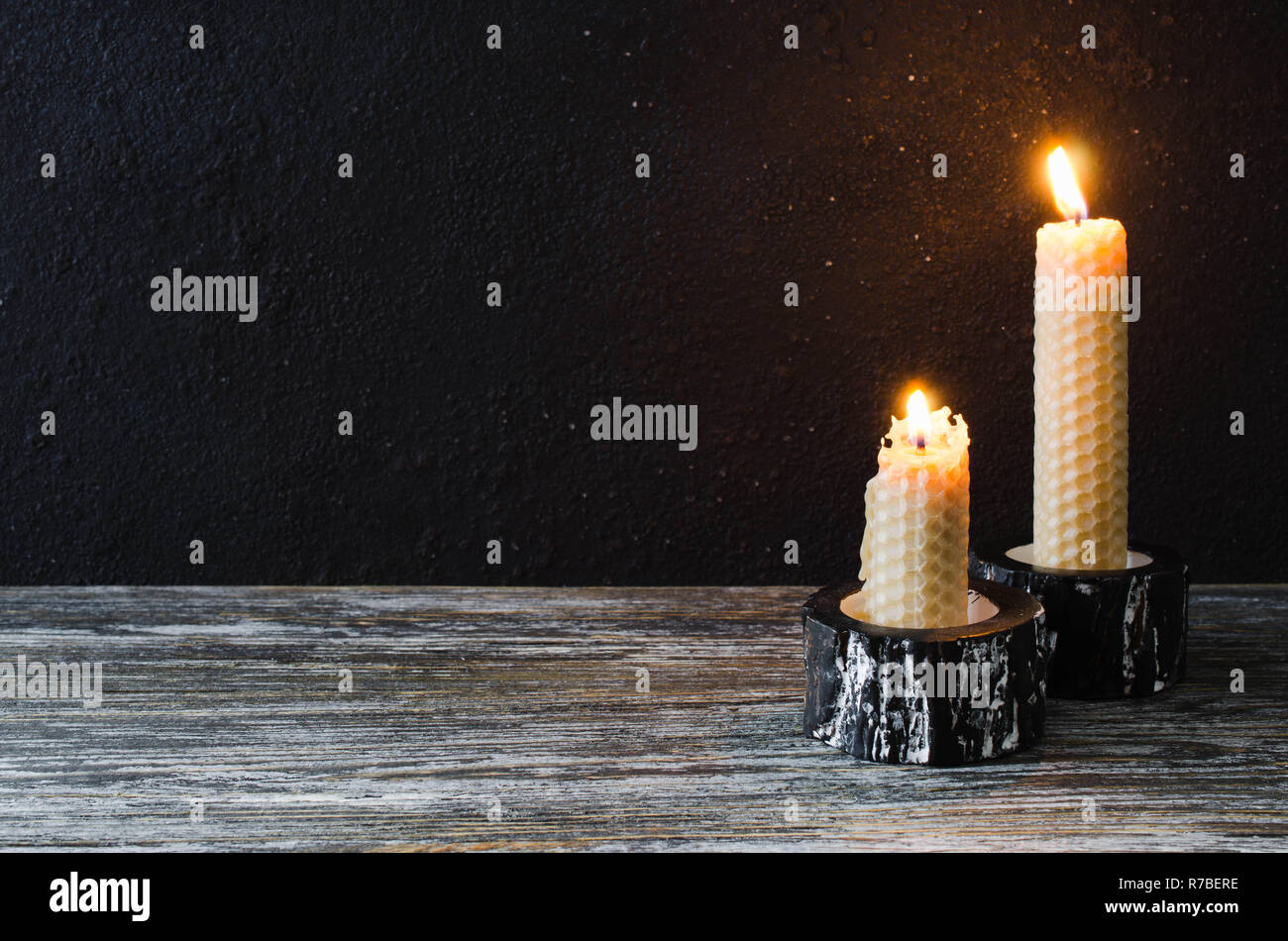 La masterizzazione di candele di cera su un vecchio tavolo di legno. Mistica scuro dello sfondo. Foto Stock