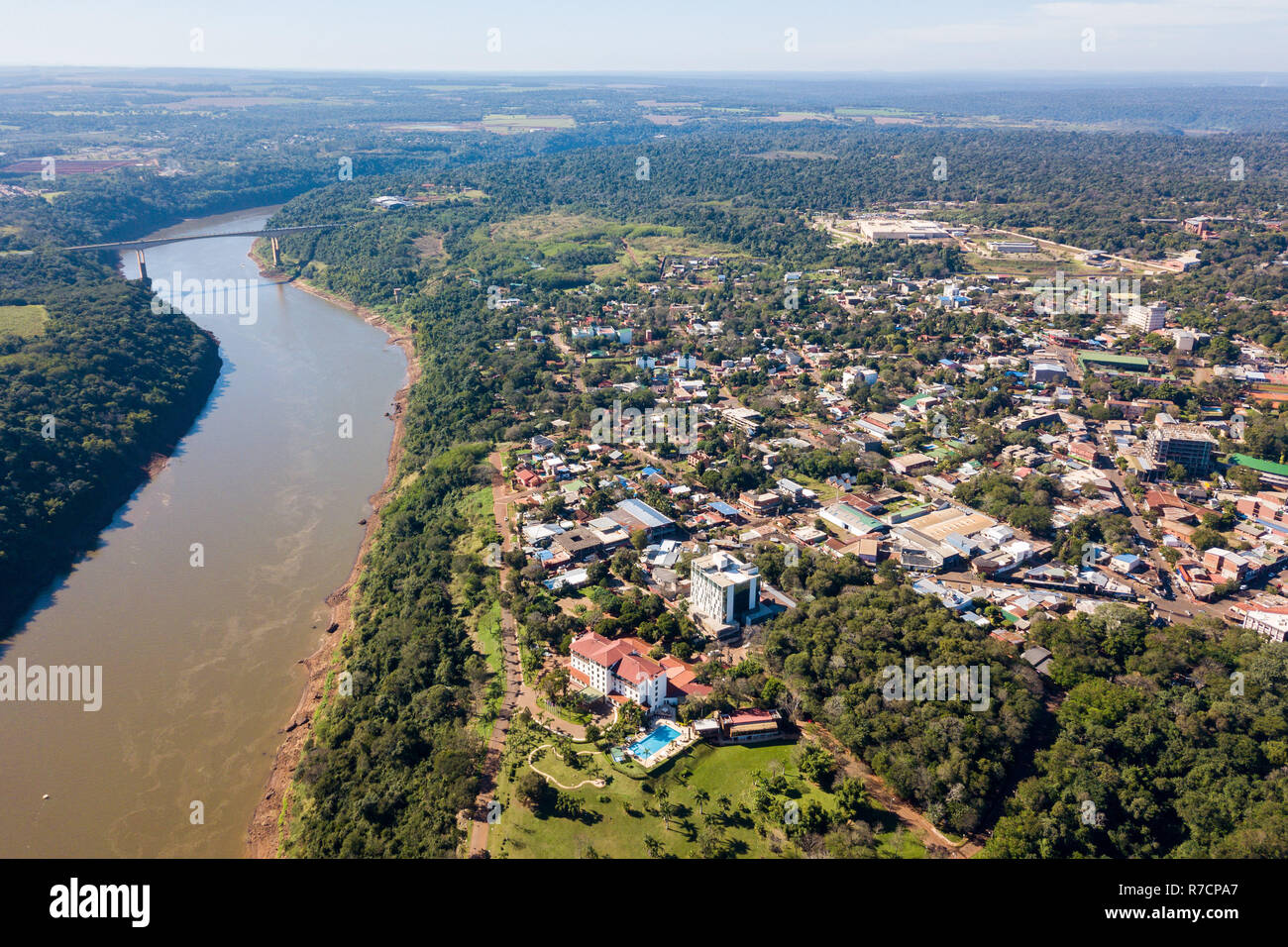 La città di Puerto Iguazú centro città vista aerea. Tancredo Neves Bridge (ponte di fraternità) valico di frontiera Brasile-Argentina oltre il Fiume Iguassu in ba Foto Stock