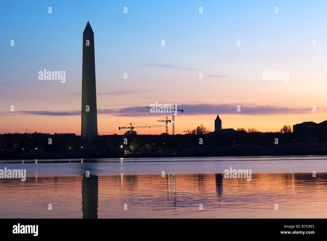 Il Monumento a Washington all'alba con lo skyline della città sullo sfondo. Riflessi colorati nel bacino di marea acque. Foto Stock