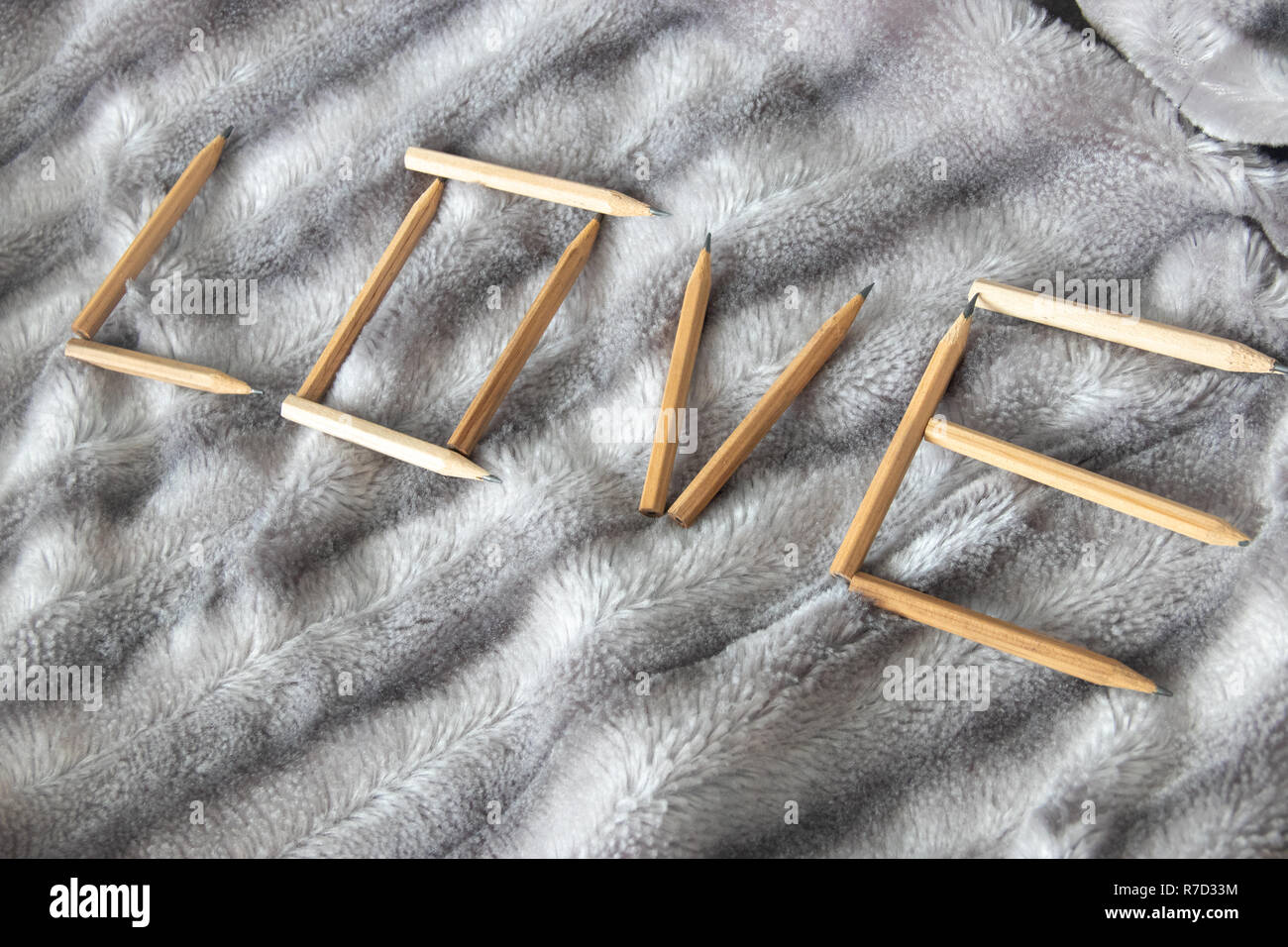 Diagonale amore scritta parola fatta di matite in legno sul grigio argento soffice pelliccia di sfondo coperta Foto Stock