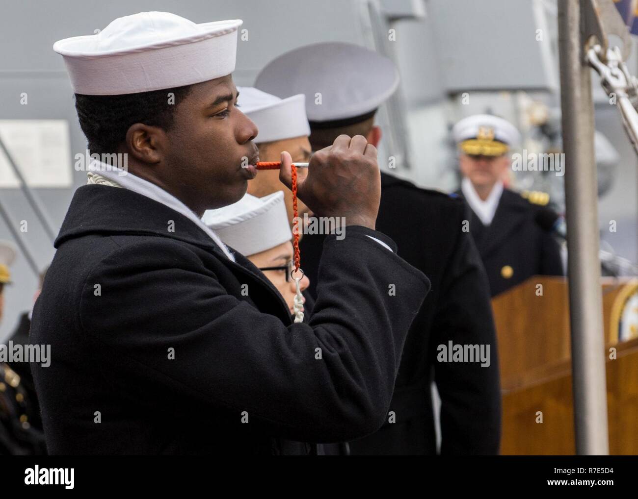 BOSTON (dec. n. 1, 2018) Nostromi Mate 3° di classe Jeron Hancock, da Cleveland, utilizza un boatswain il tubo durante la messa in funzione di cerimonia per la USS Thomas Hudner (DDG 116) a Cruiseport Boston. DDG 116 è la 66Arleigh Burke-class destroyer e la prima nave da guerra chiamato per Capt. Thomas J. Hudner, Jr., che hanno guadagnato la medaglia d'onore per le sue azioni durante il tentativo di salvare la vita del suo wingman, alfiere di Jesse L. Brown, durante la Battaglia di Chosin serbatoio nella guerra coreana. Stati Uniti Navy Foto Stock