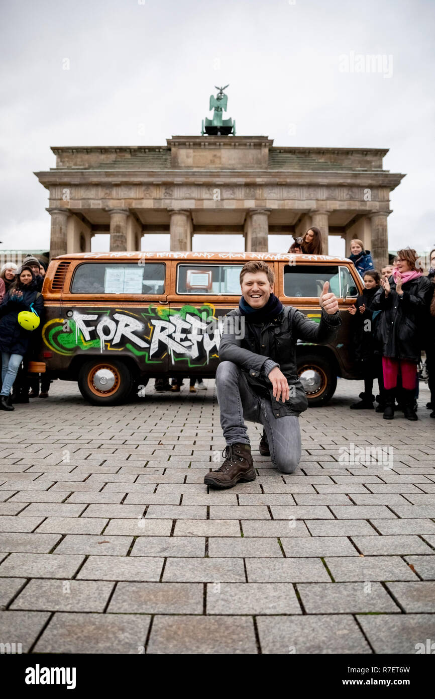 Berlino, Germania. 09Dec, 2018. Grigorij Richters, direttore della pellicola, si inginocchia davanti alla Porta di Brandeburgo quando arriva. Richters camminato da Parigi via Bruxelles a Berlino accompagnato da un bus VW come parte della sua iniziativa "Un milione di passaggi per il soccorso di 1.000 bambini del campo profughi". Credito: Christoph Soeder/dpa/Alamy Live News Foto Stock