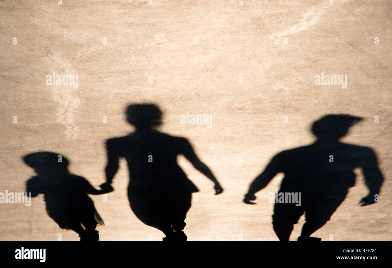 Sfocata ombra di genitori e figlia passeggiando sul lungomare di estate Foto Stock