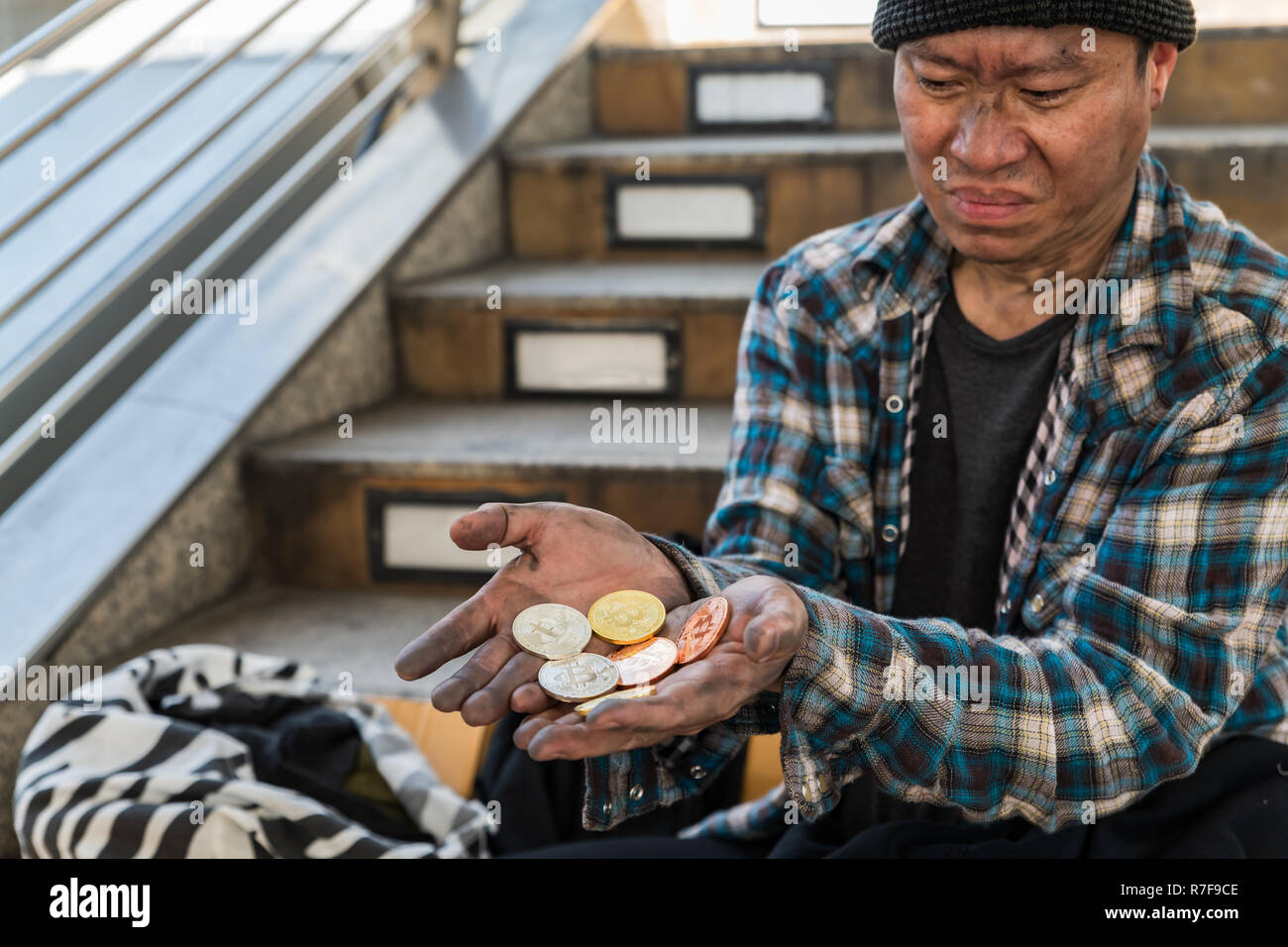 Deluso faccia espressione di un maschio di senzatetto mendicante con la manciata di monete bitcoin - svalutazione del concetto bitcoin Foto Stock