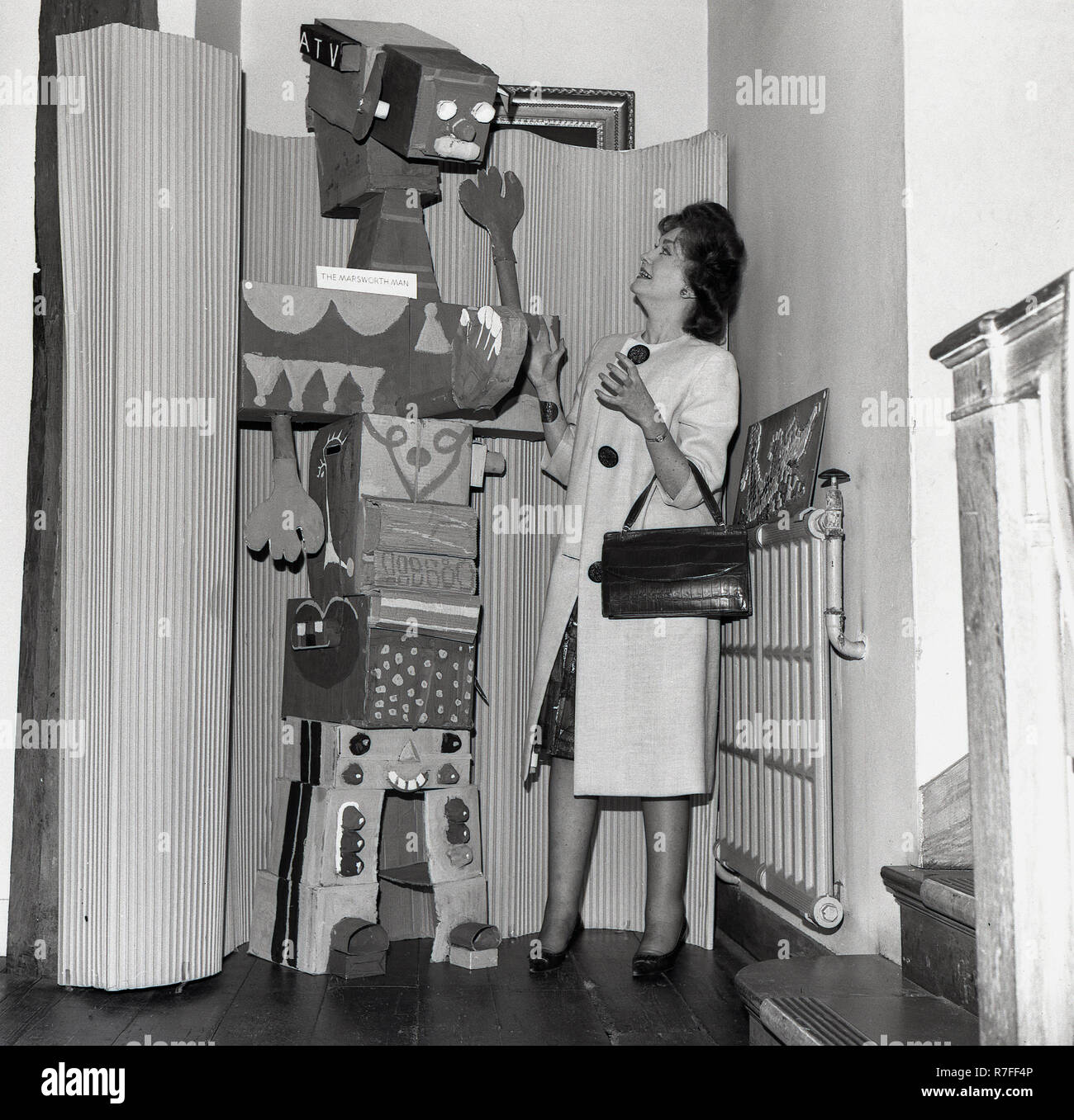 1965, signora governatore presso una scuola in piedi da "l'uomo Marsworth', un alto robot di cartone che gli alunni di una classe della scuola aveva fatto, Inghilterra, Regno Unito. Fu agli inizi degli anni sessanta che erano stati fatti tentativi per ottenere un veicolo spaziale a volare per il pianeta Marte e nel 1965 la NASA Mariner 4 navicella spaziale ha fatto finalmente. Foto Stock