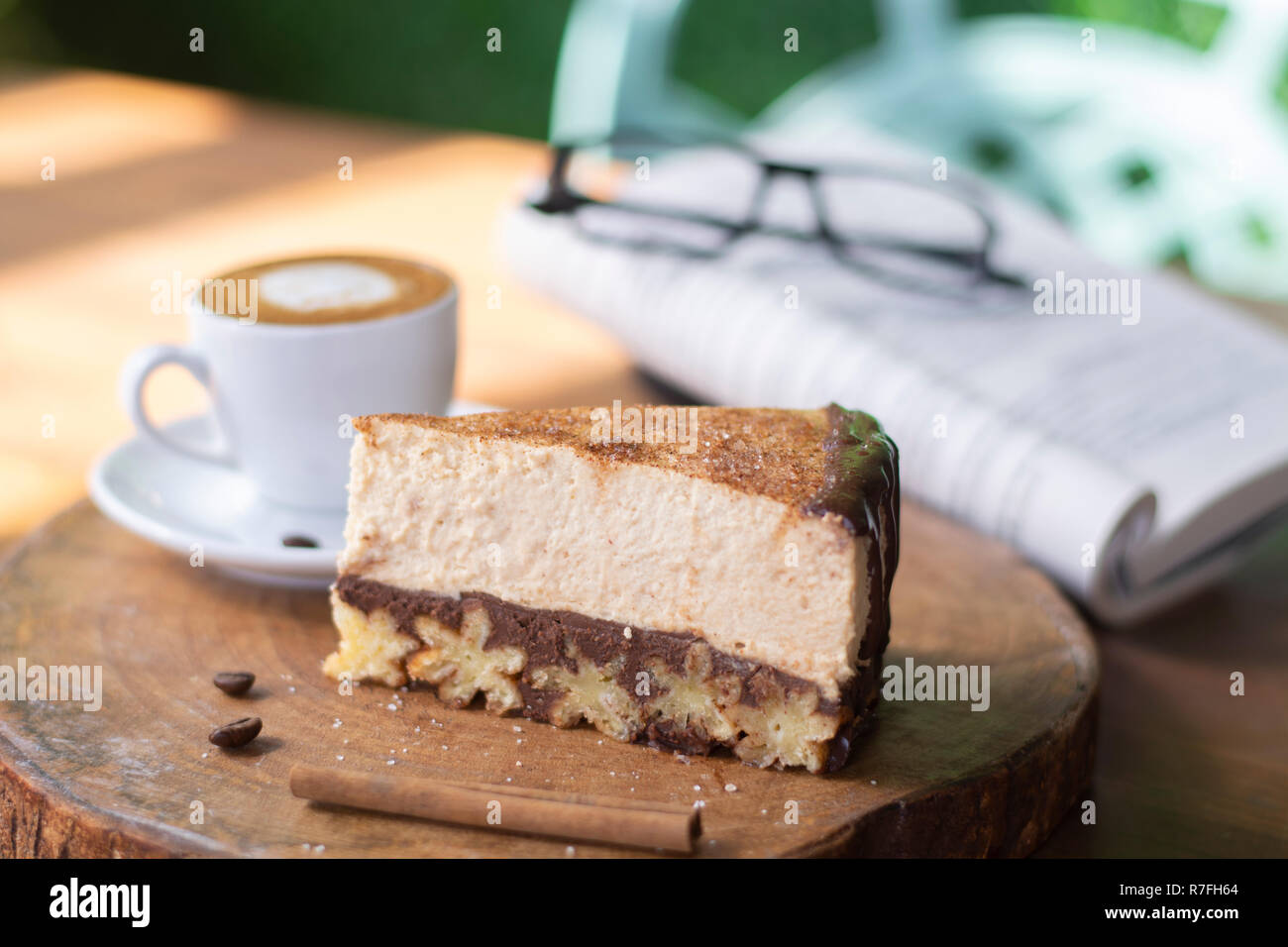 Churros cheesecake e caffè macchiato con libro e bicchieri sfondo sulla tavola di legno Foto Stock