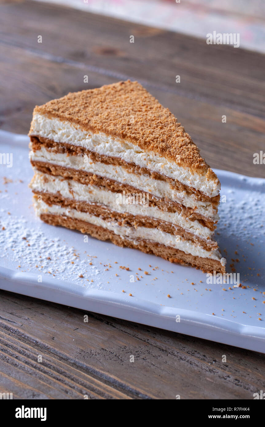 La deliziosa torta di miele sulla piastra bianca sulla tavola di legno Foto Stock