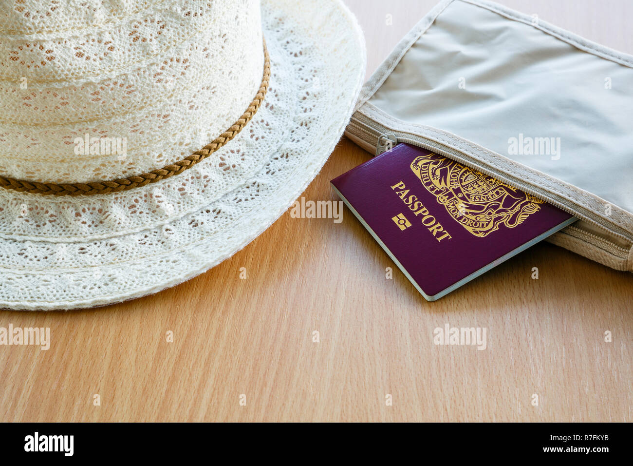 Concetto di viaggio per viaggiare all'estero passaporto biometrico britannico in un portafoglio con cappello da donna su un tavolo. Inghilterra, Regno Unito, Gran Bretagna Foto Stock