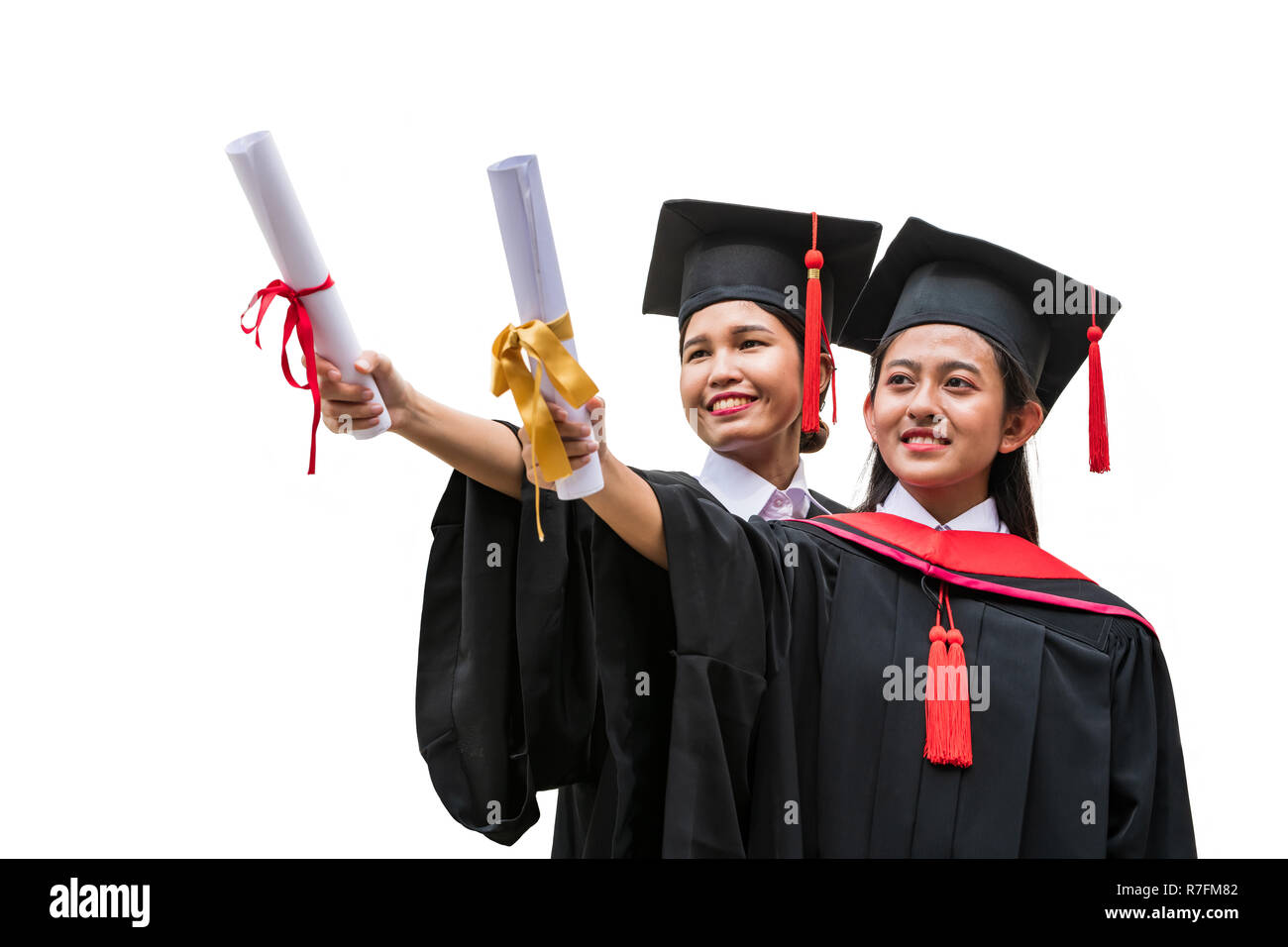 Due donne gli studenti asiatici in abito di graduazione tenendo i diplomi con le mani in avanti di stiramento Foto Stock