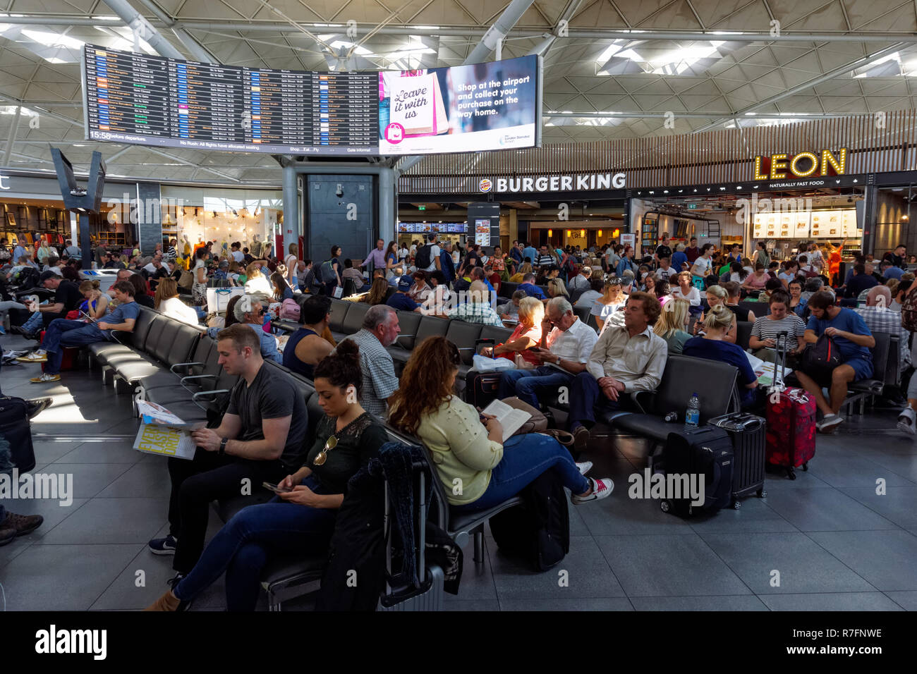 I passeggeri in attesa nella lounge delle partenze presso l'aeroporto Stansted di Londra, Inghilterra, Regno Unito Foto Stock