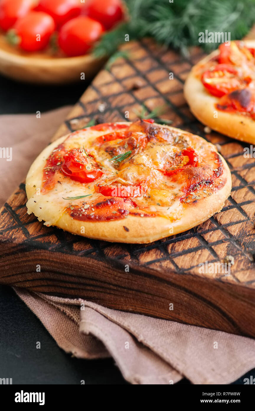 Mini pizze margheritas su servita su una tavola di legno. La parte posteriore in legno Foto Stock