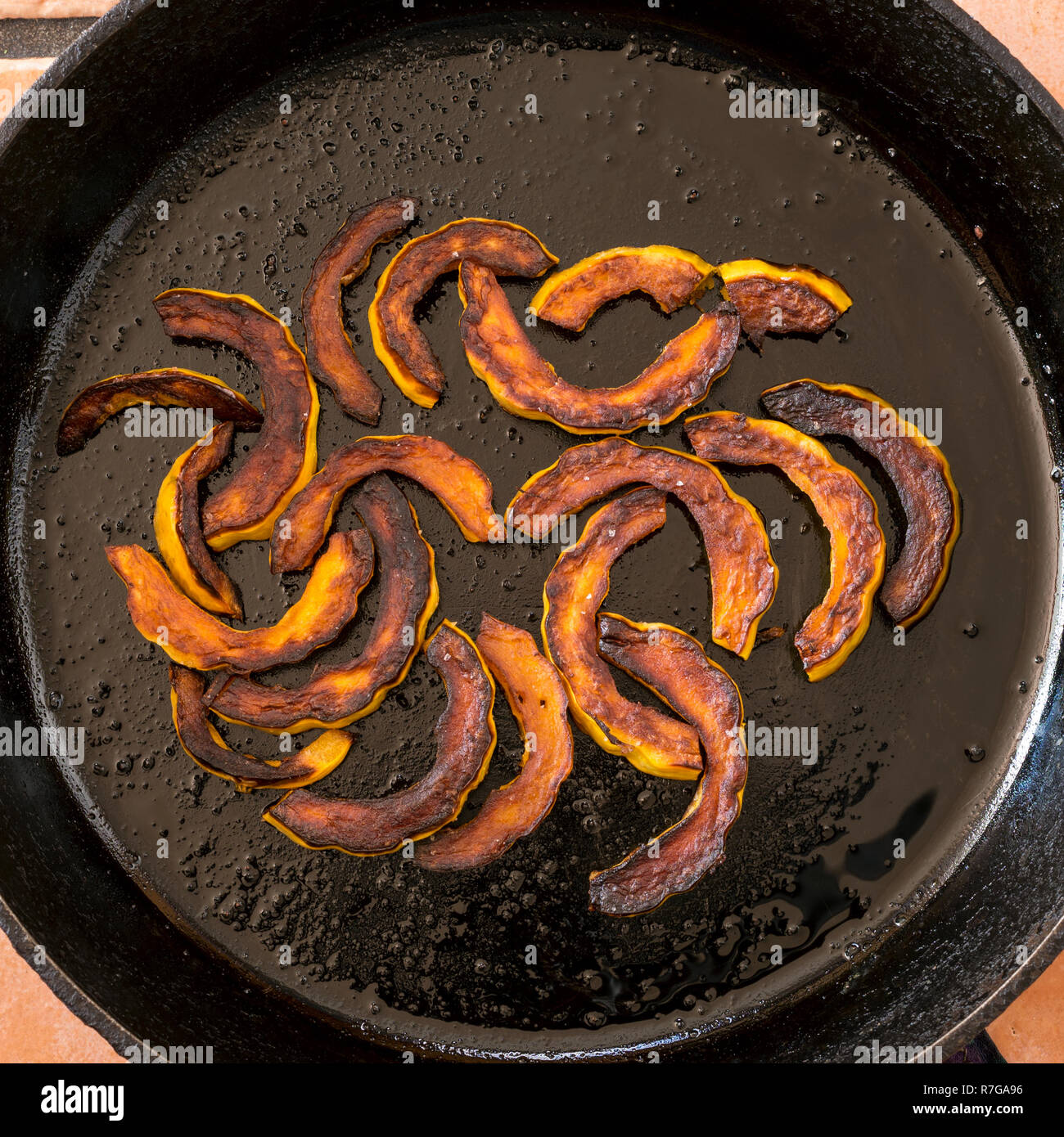 Saltata di zucche invernali fette in una padella in ghisa. Foto Stock