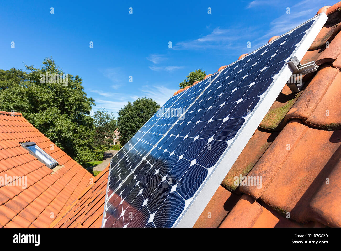 Riga blu di collettori solari sul tetto arancione di casa Foto Stock