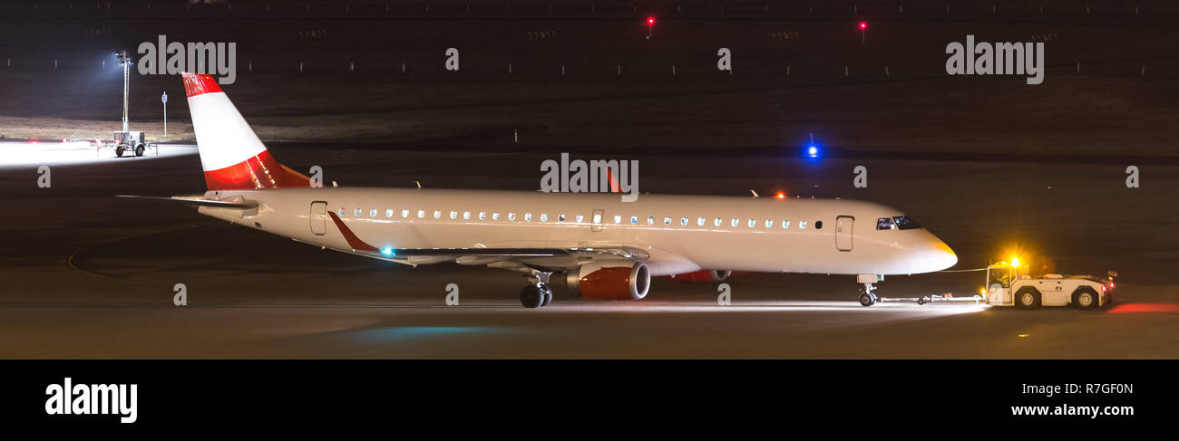 Un aereo beeing trainato durante la notte in un aeroporto Foto Stock