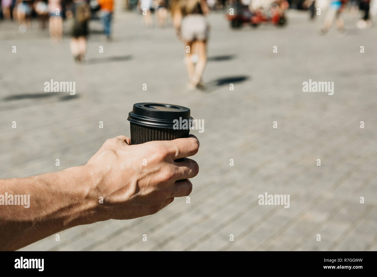 Primo piano di un uomo su una strada di città tenendo un caffè o altre bevande da asporto nella sua mano. Stile di vita Foto Stock