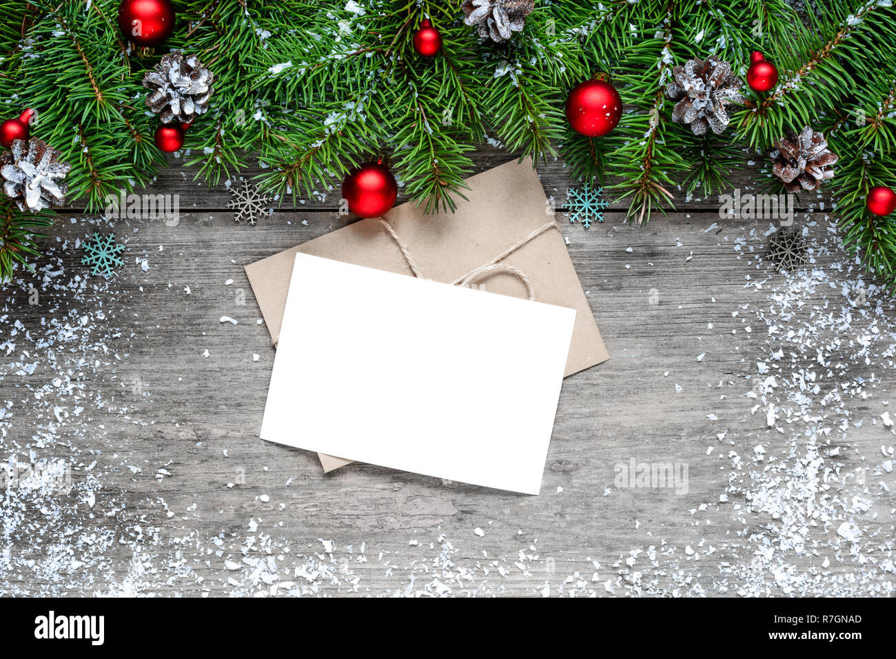 Auguri di Natale carta con abete rami e decorazioni su legno rustico sfondo. mock up. laici piatta Foto Stock