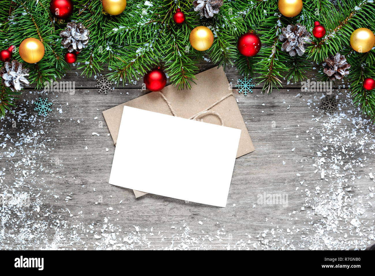 Auguri di Natale carta con abete rami e decorazioni su rustico sfondo di legno ricoperta di neve. mock up. laici piatta Foto Stock