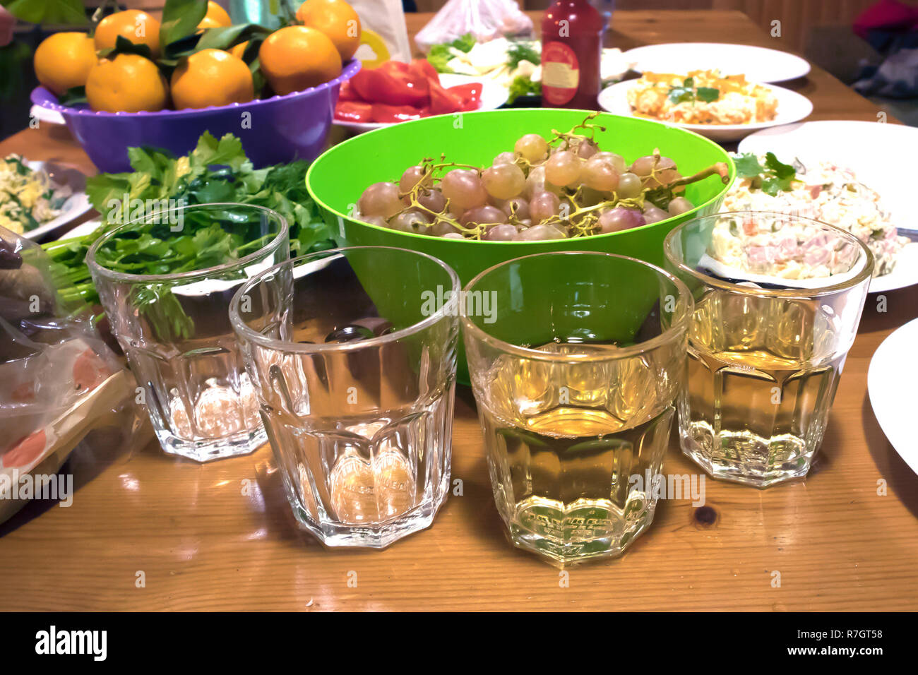 Quattro bicchieri su un rustico tavolo partito closeup, due vuoti e due con vino bianco Foto Stock