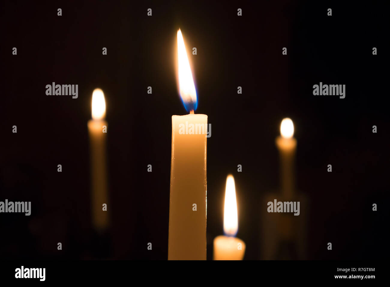 Un numero di fusi di masterizzazione candele con forche offuscata della fiamma contro uno sfondo scuro Foto Stock