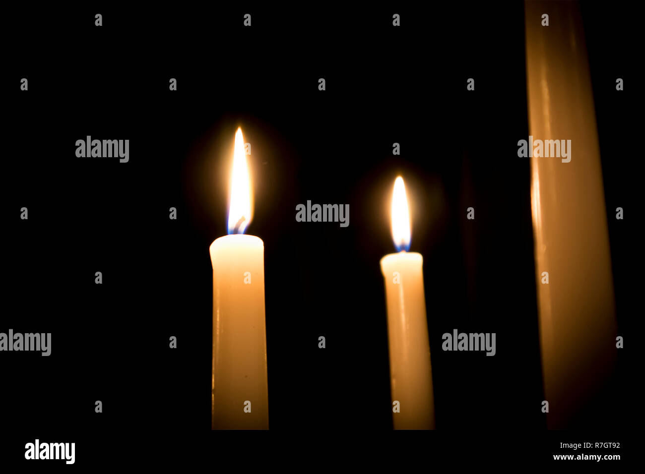 La masterizzazione di tre candele fuso con forche offuscata della fiamma contro uno sfondo scuro Foto Stock