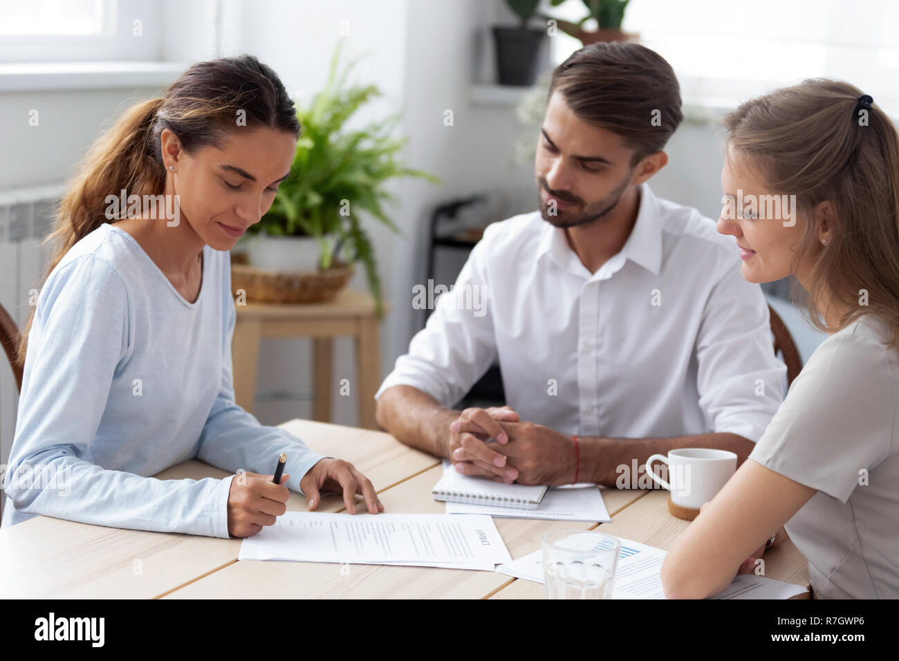 Diverse persone sedute alla scrivania biracial femmina del lavoro firma co Foto Stock