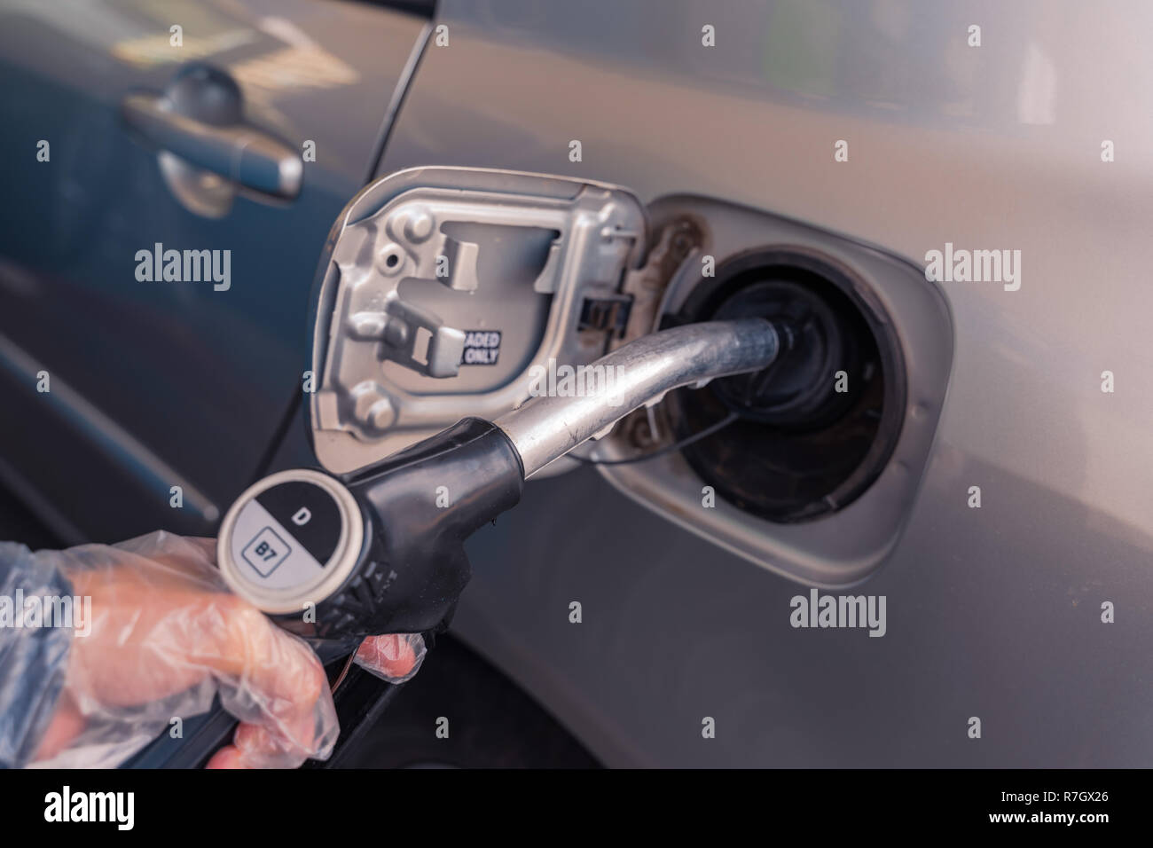 Pistole carburante a livello europeo la stazione di benzina. Donna mettendo mano Gasolio B7 carburante pistola nero al serbatoio del combustibile. Focus sulla pistola, DD firmare al di fuori del Foto Stock