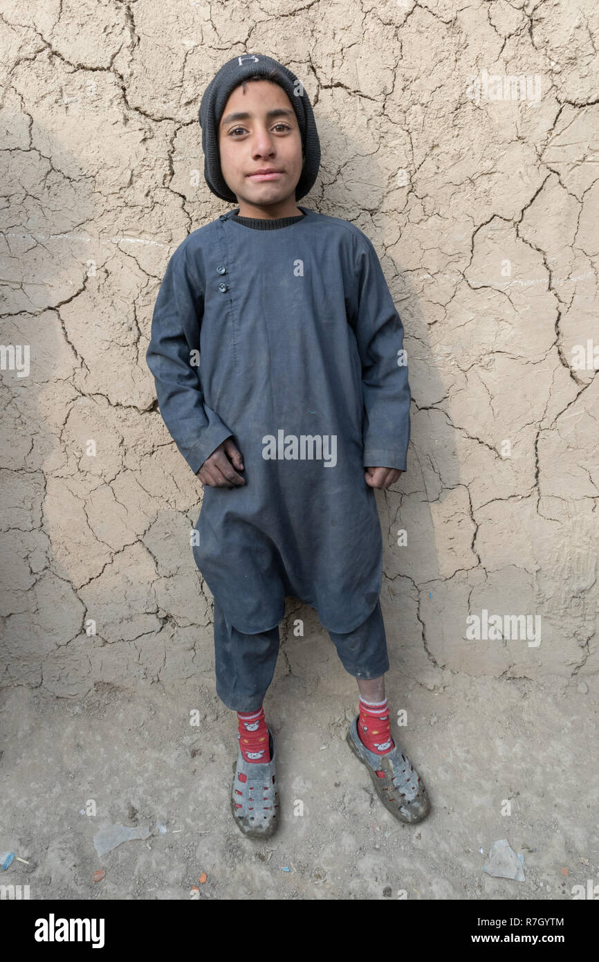 Ragazzo la cui famiglia è stata spostata dalla provincia di Helmand a causa dei talebani. Egli vive in condizioni difficili in un campo di rifugiati vicino a Kabul, Afghanistan. Foto Stock