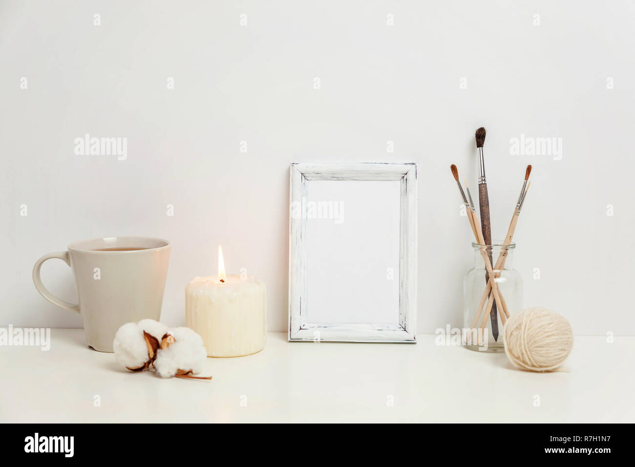 Telaio verticale mockup con tazza di caffè, candela vicino a muro bianco. Fotogramma vuoto mock up per la progettazione della presentazione. Inquadratura del modello di arte moderna. Hygge sca Foto Stock