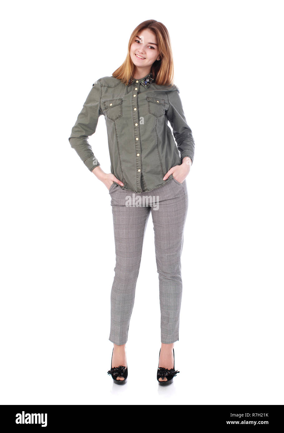 Giovane bella ragazza bionda in grigio pantaloni e camicia verde, isolato su sfondo bianco Foto Stock