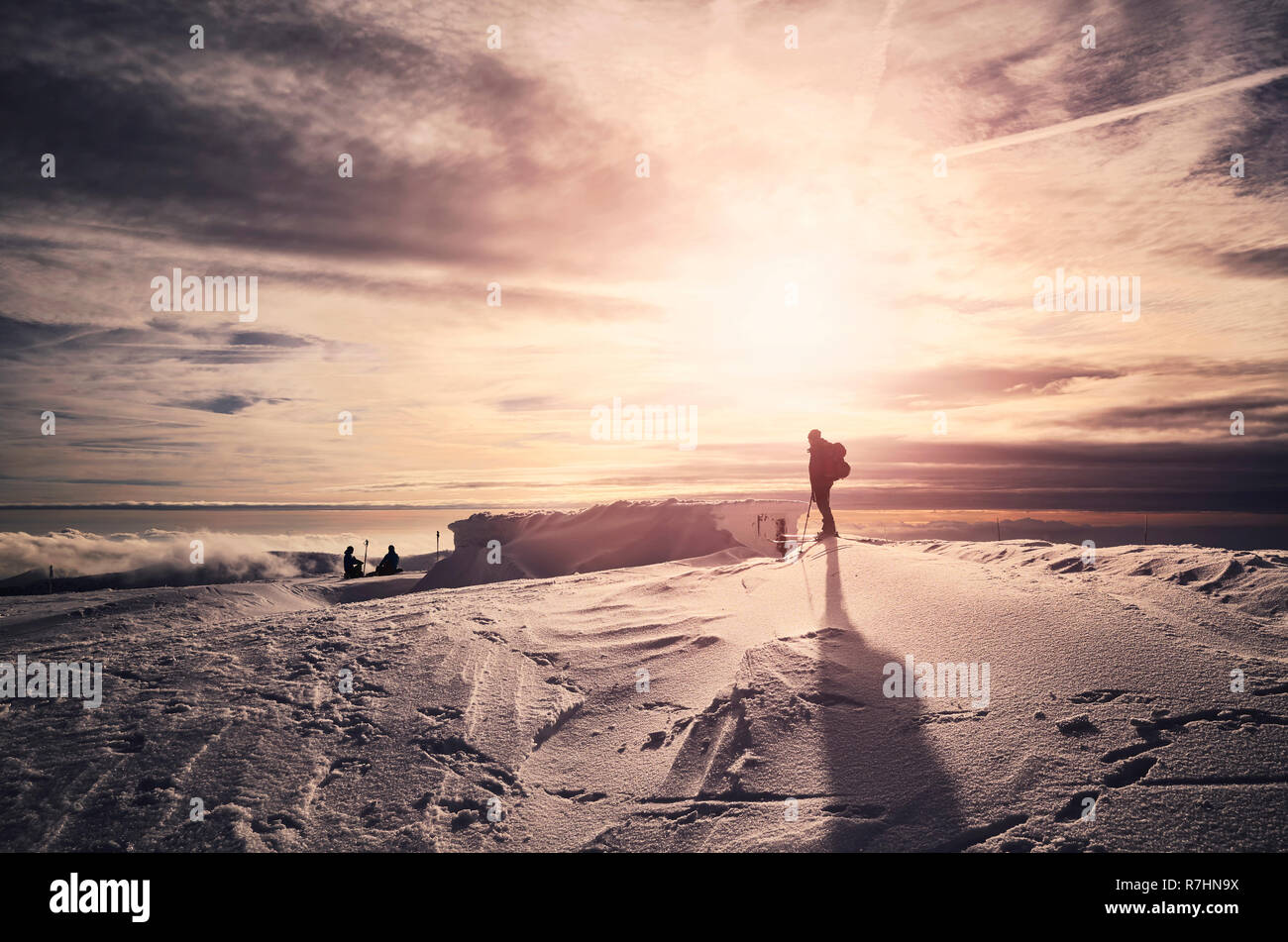In inverno le montagne con appoggio sagome sciatori al tramonto, dai toni di colore dell'immagine. Foto Stock