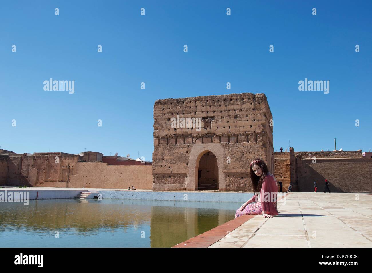 Una bruna lady si siede da uno stagno in un antico palazzo in Marrakech, Marocco Foto Stock