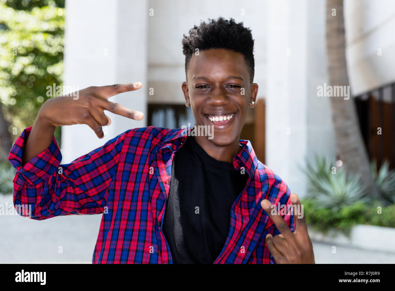Felice in posa americano africano giovane adulto uomo outdoor in città Foto Stock