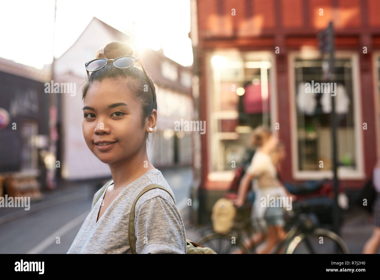 Sorridente giovane donna asiatica in piedi su una strada di città Foto Stock